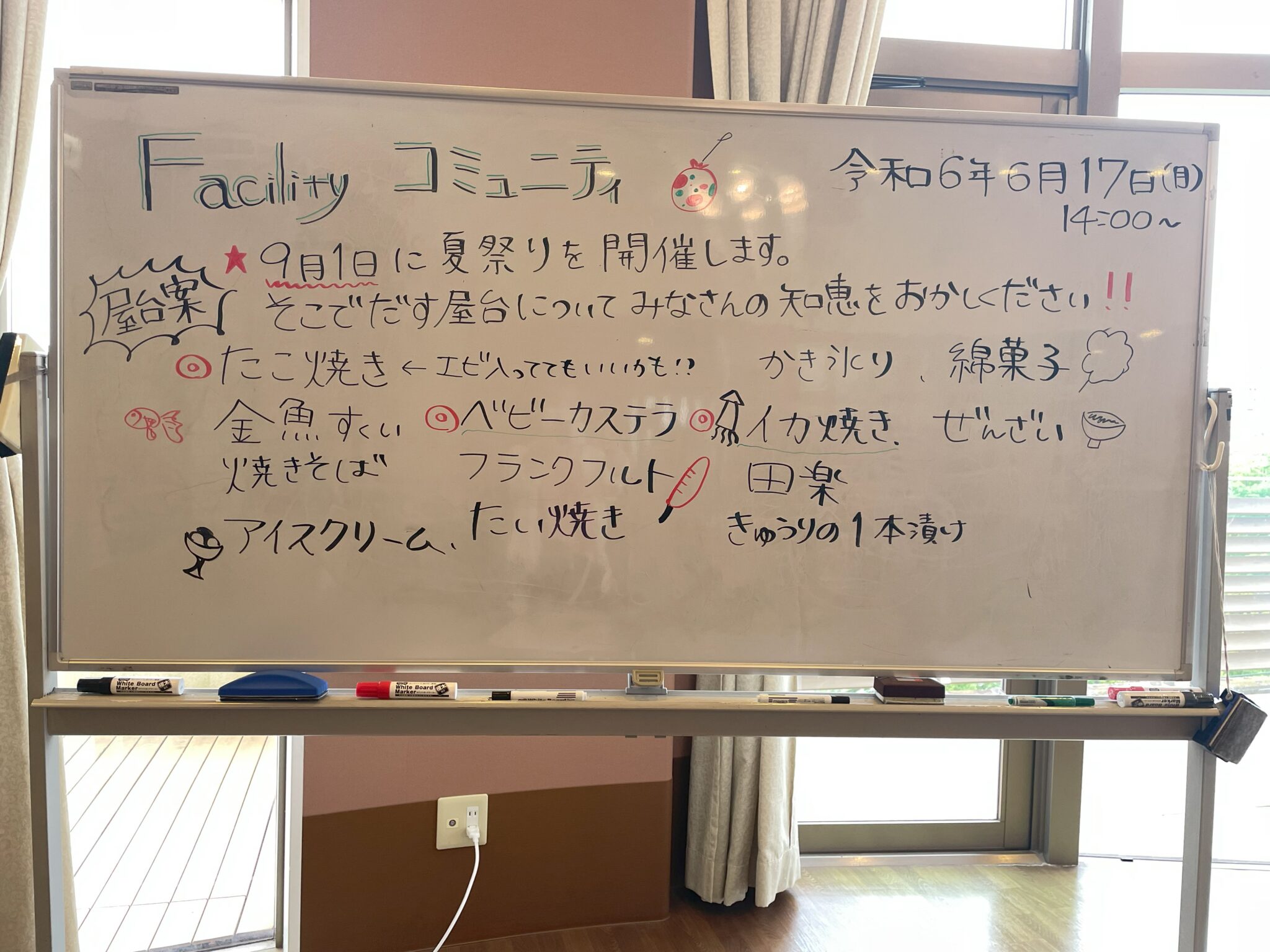 施設のイベント告知ボード。夏祭りと料理企画のメニューが手書きで記載されている